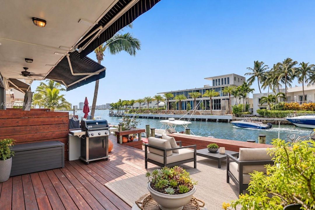 Waterfront deck featuring wood-finish flooring, a retractable awning, built-in wooden privacy screening