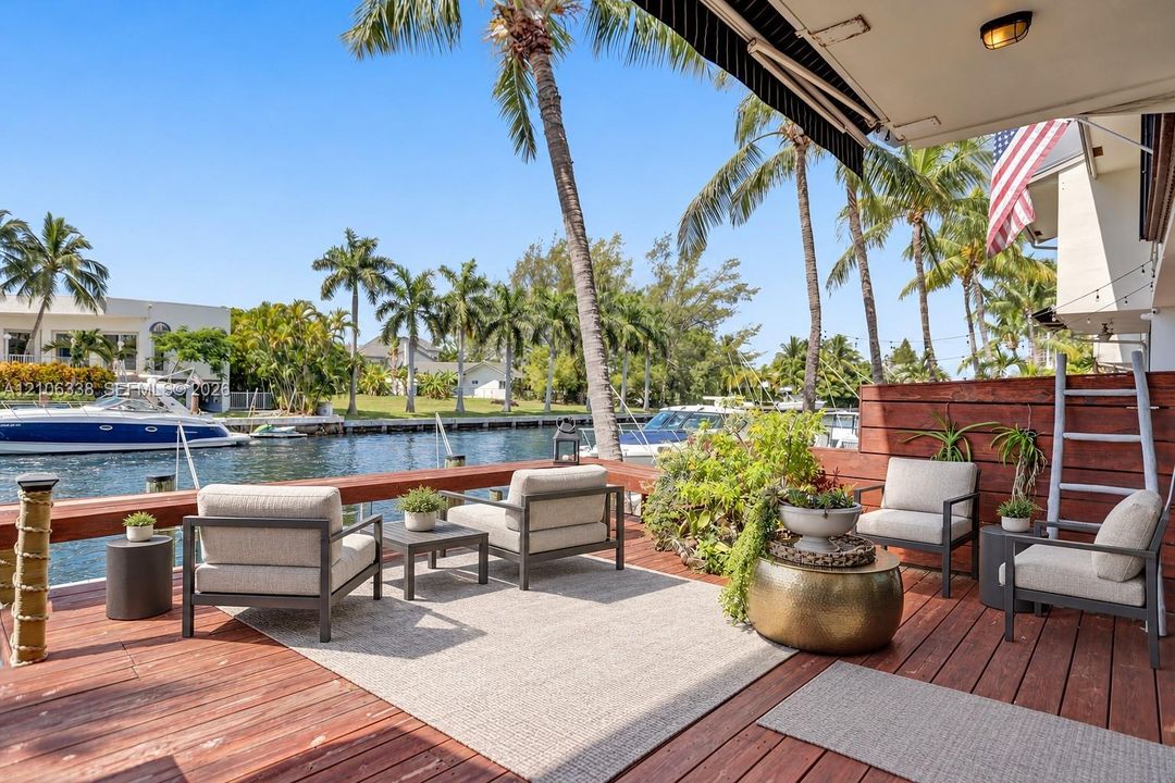 Waterfront deck featuring wood-plank flooring, horizontal wood railing, and a retractable fabric awning