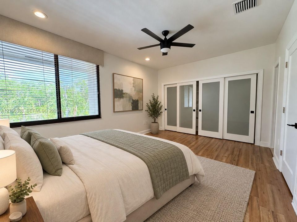 Bedroom featuring wood-finish flooring, recessed lighting, a modern ceiling fan, and sliding closet doors with frosted glass panels