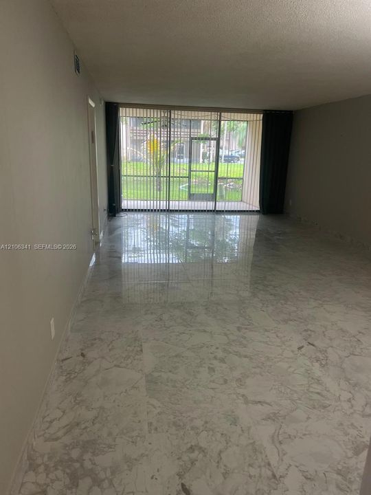 Polished stone-finish tile flooring throughout with full-height sliding glass doors leading to a screened enclosure