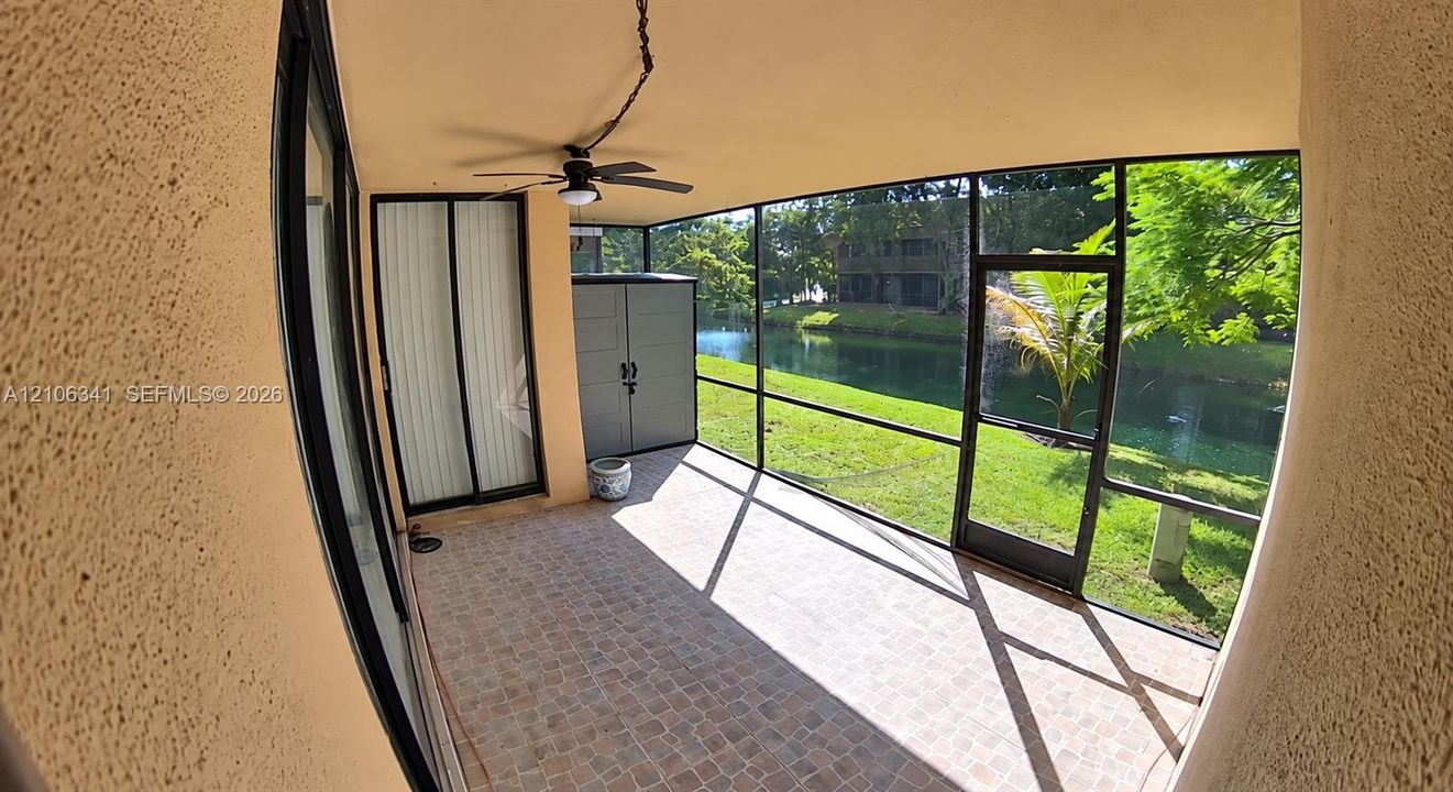 Screened-in lanai featuring tiled flooring, a ceiling fan, and sliding glass door entry
