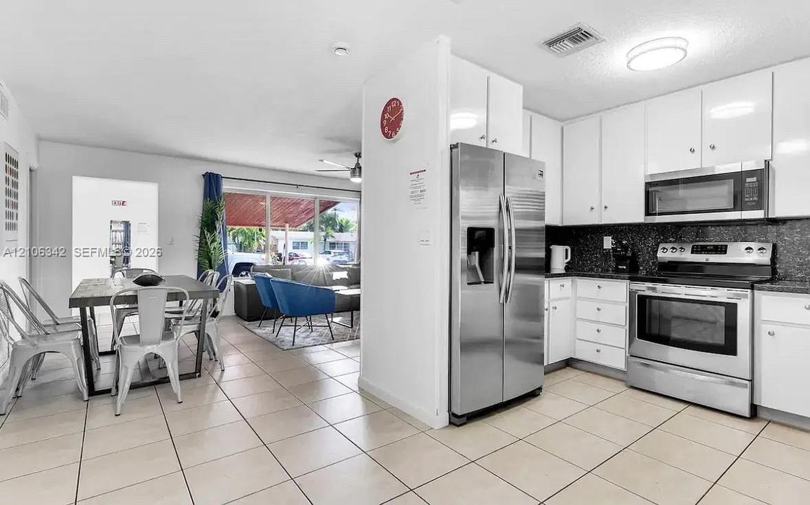 Kitchen featuring white cabinetry, stainless steel appliances, and dark countertops, complemented by tile flooring
