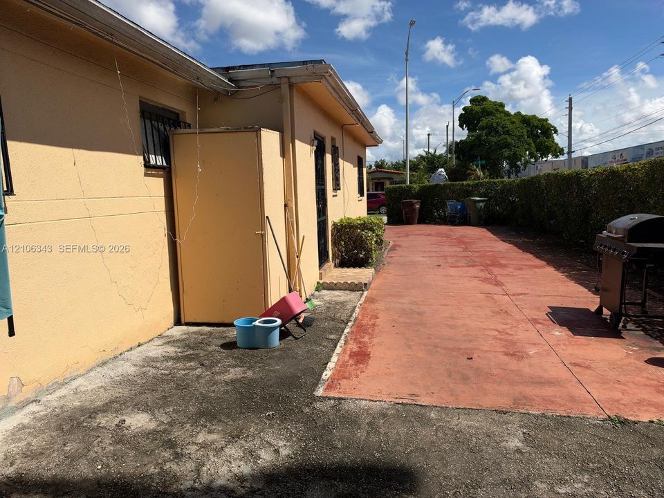 Stucco exterior with concrete side yard and perimeter privacy hedge