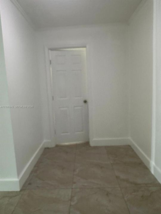 Neutral-toned floor tiles featuring large-format square composition and a six-panel interior door
