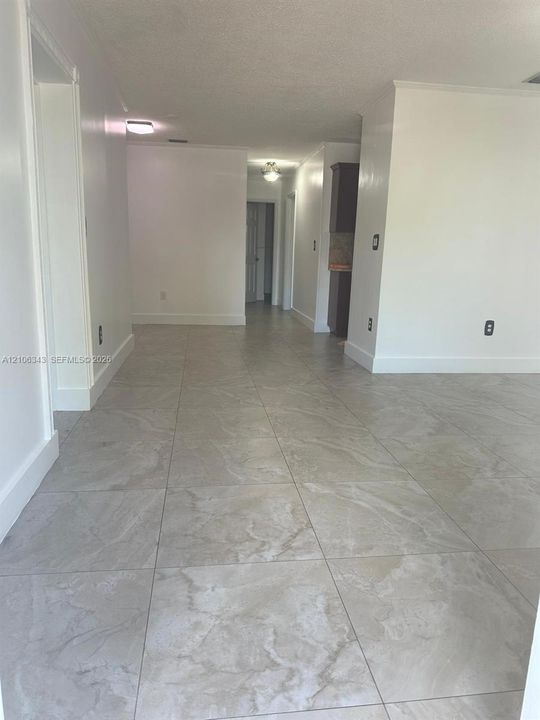 Large-format tile flooring, neutral wall paint, and overhead flush-mount lighting