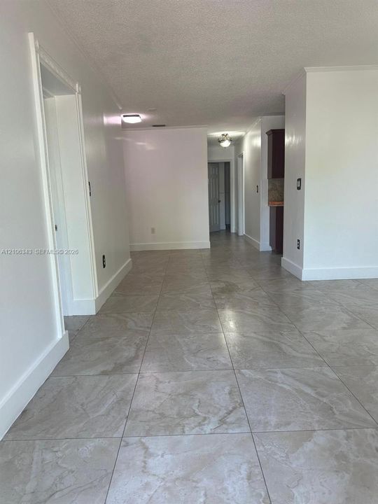 Large-format stone-style tile flooring, neutral wall finishes, and flush-mount lighting fixtures