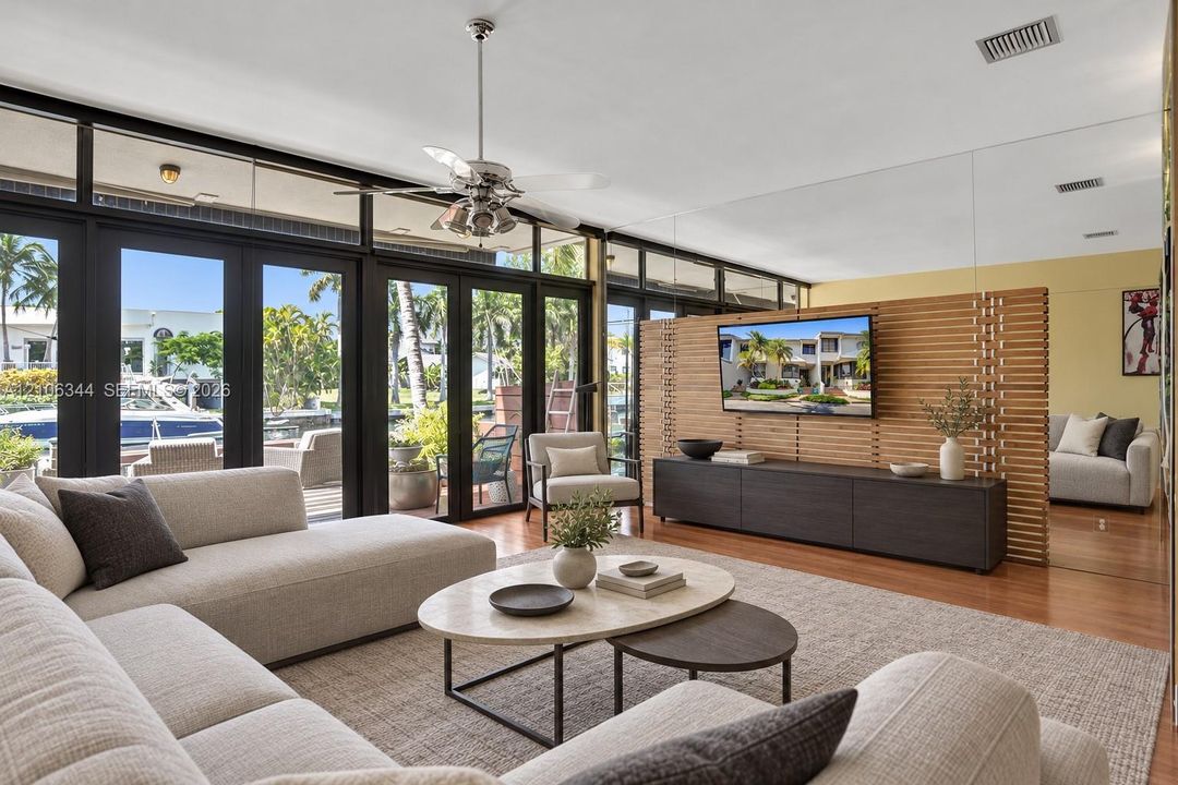 Floor-to-ceiling glass paneling with dark-framed exterior doors, horizontal wood-slat room divider, mirror-paneled wall, and wood-finish flooring