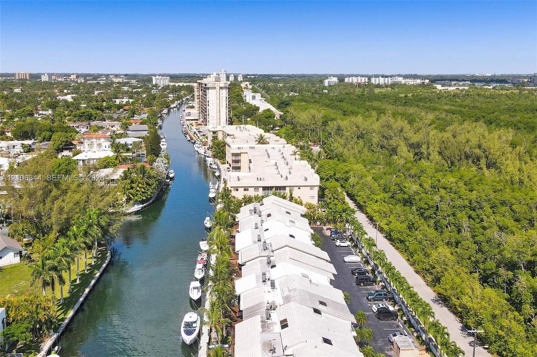 Waterfront property featuring a canal-side bulkhead with private boat slips, multi-level residential structures with pitched rooflines, and paved surface parking