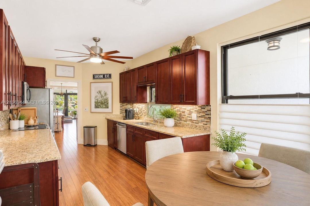 Kitchen featuring dark wood cabinetry, stone-finish countertops, a mosaic tile backsplash, stainless steel appliances, and wood-finish flooring