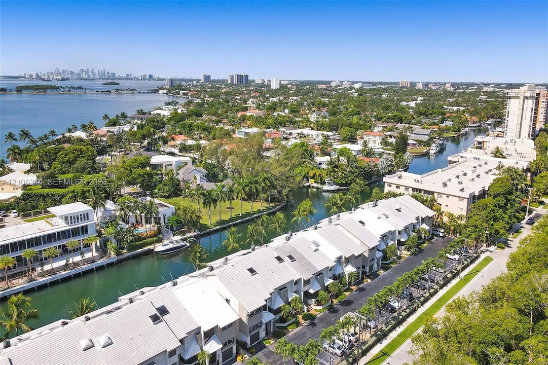 Aerial perspective of waterfront properties featuring deep-water canal access, private boat slips, mature palm trees, and proximity to open bay waters