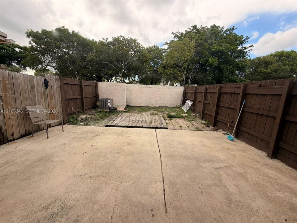 Private backyard featuring a concrete patio, wood-finish decking, and enclosed by wood privacy fencing