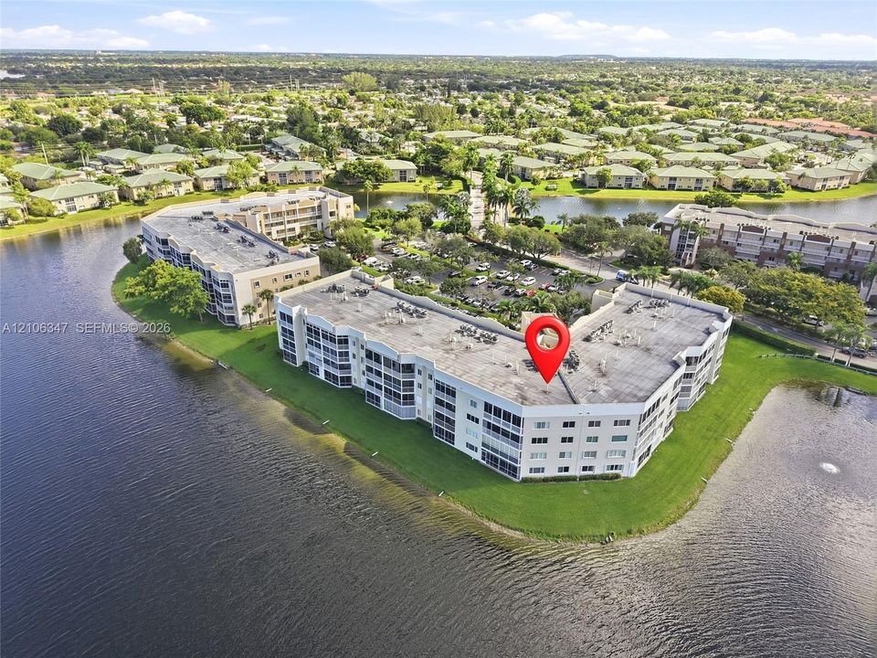 Multi-story residential building situated on a waterfront lot featuring manicured landscaping and perimeter walking areas