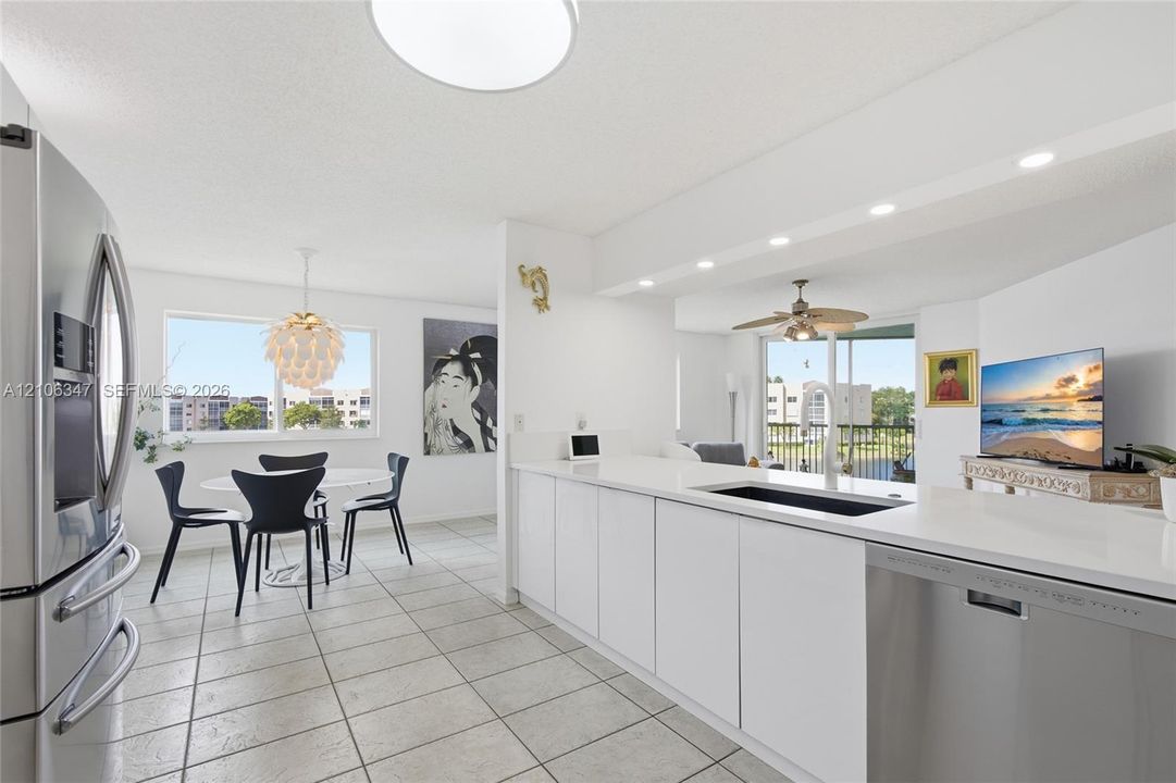 Kitchen featuring white flat-panel cabinetry, solid-surface countertops, recessed lighting, tile flooring, and stainless steel appliances