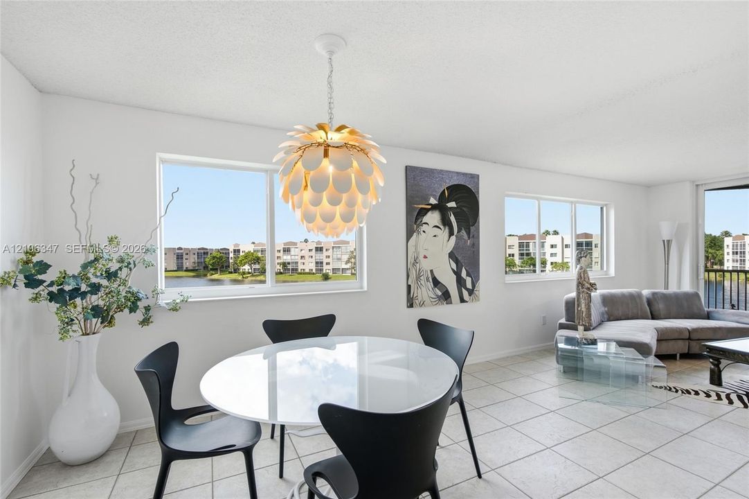 Open-concept interior featuring large-format ceramic tile flooring, multiple windows providing natural light, and a decorative petal-style pendant light fixture
