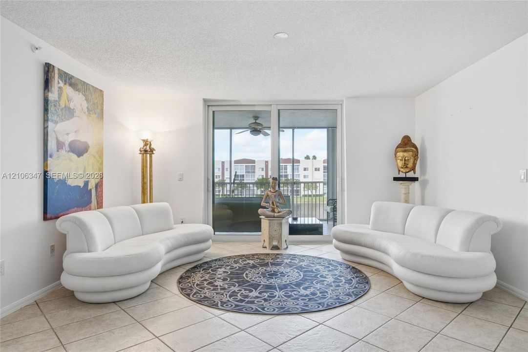 Living area featuring large-format ceramic tile flooring and full-height sliding glass doors with direct access to a screened-in balcony