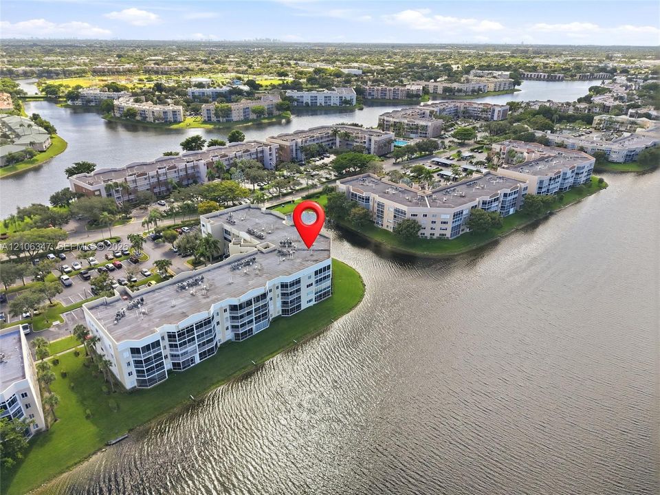 Waterfront multi-story residential building situated on a peninsula with panoramic canal water frontage and established landscaping