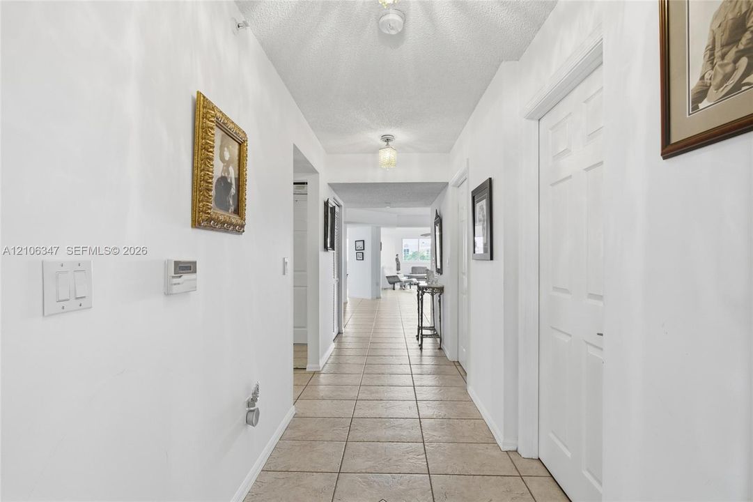 Hallway featuring neutral tile flooring, smooth white walls, recessed lighting, and six-panel interior doors