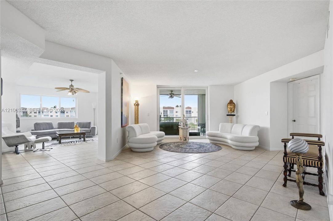 Open-concept interior featuring large-format neutral floor tile, sliding glass doors providing outdoor access, and a dual-ceiling fan configuration