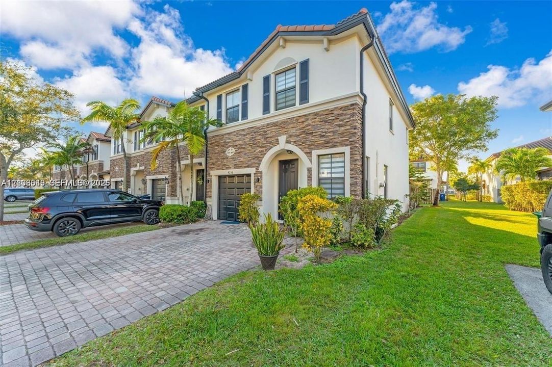 Two-story residence featuring a stone veneer facade, paver driveway, single-car garage, and architectural shutters