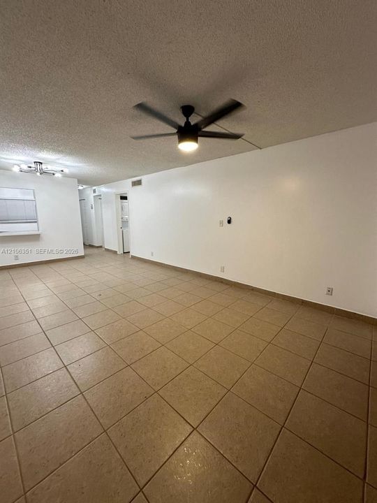 Large-format ceramic tile flooring, ceiling fan with integrated lighting, textured ceiling finish, and built-in service window