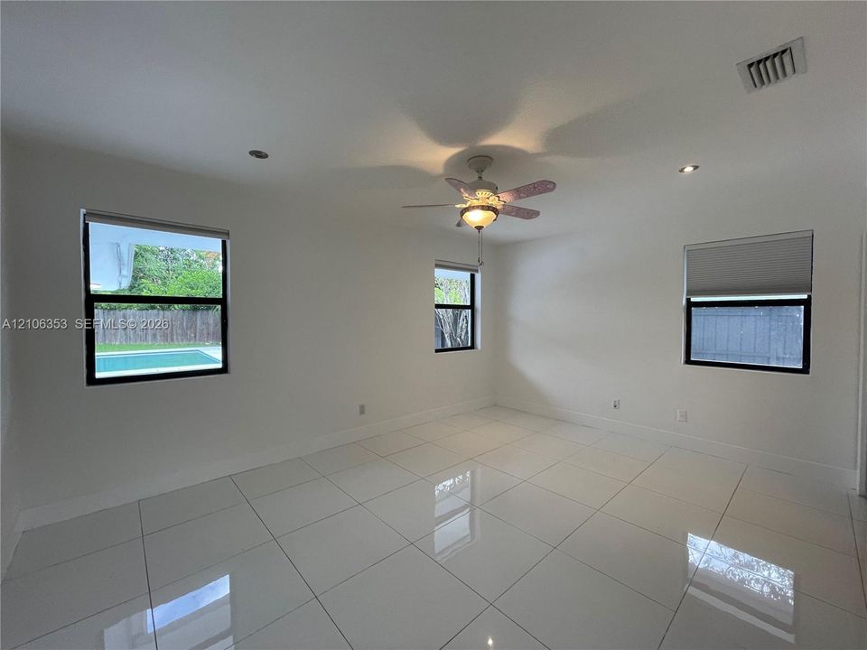 Polished large-format tile flooring, recessed lighting, ceiling fan with integrated lighting, and multiple windows with roller shades