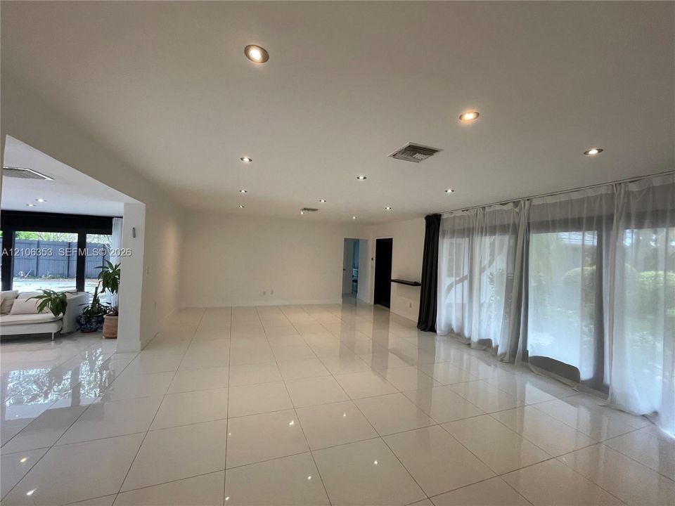 Open-concept interior featuring large-format tile flooring, recessed ceiling lighting, and floor-to-ceiling glass panel doors