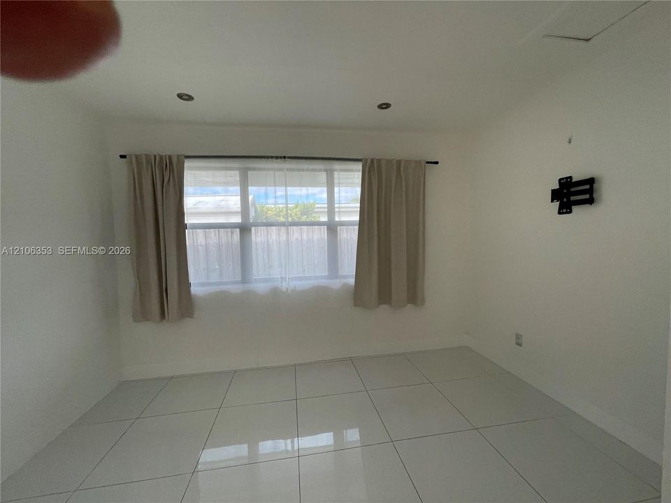 Large-format tile flooring, recessed ceiling lighting, and a multi-pane horizontal window featuring a metal curtain rod
