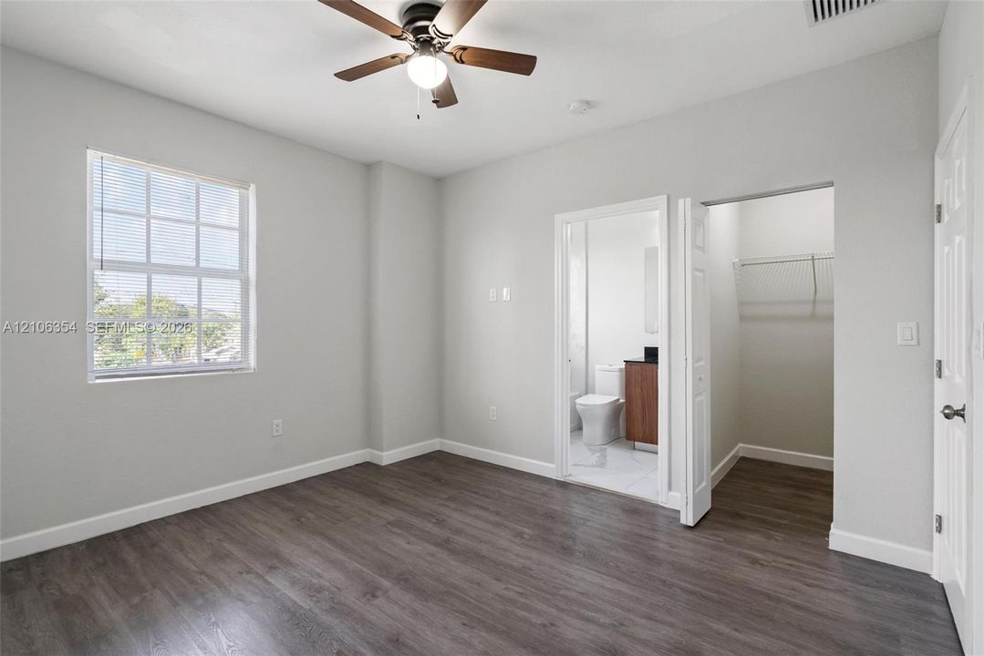 Room featuring wood-finish flooring, a multi-pane window, and a ceiling fan with integrated lighting