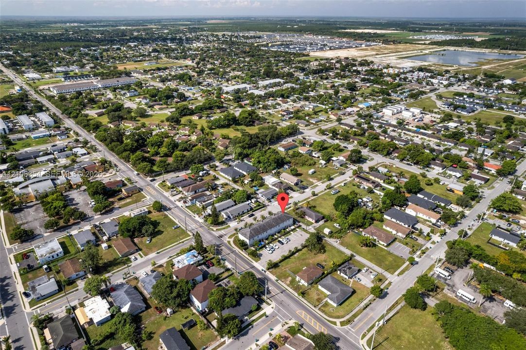 Aerial perspective of a multi-unit residential structure featuring a multi-pitched roofline and dedicated surface parking