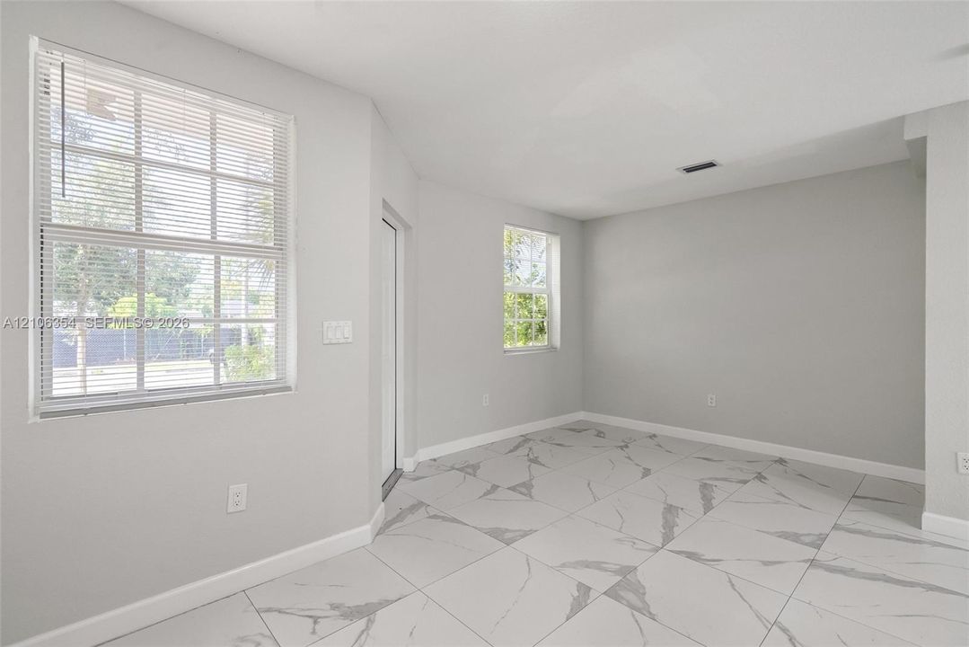 Neutral interior space featuring large-format stone-style tile flooring with veining, light grey walls, and dual double-pane windows