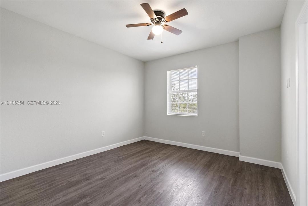 Neutral wall finishes, wood-finish flooring, multi-pane window, and central ceiling fan with integrated lighting