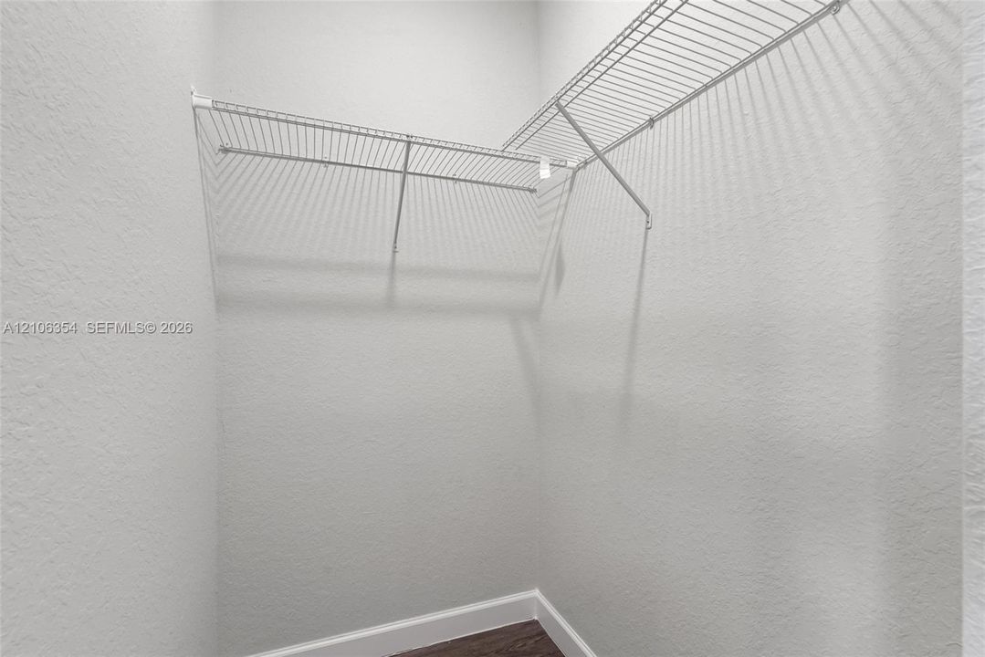 Storage area featuring white textured walls, wood-finish flooring, and multi-tier wire shelving