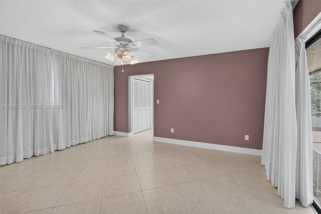 Interior space featuring tile flooring, ceiling fan with integrated lighting, and louvered closet doors