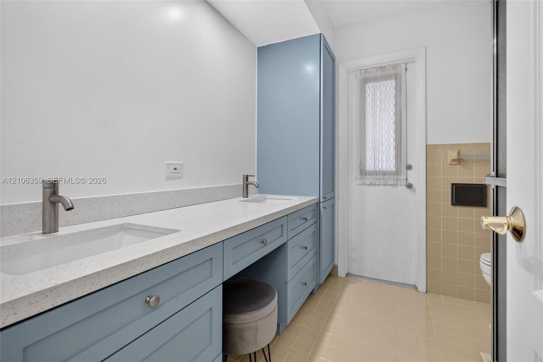 Custom dual-vanity cabinetry in blue finish with stone-composite countertop, dual undermount sinks, and designer fixtures