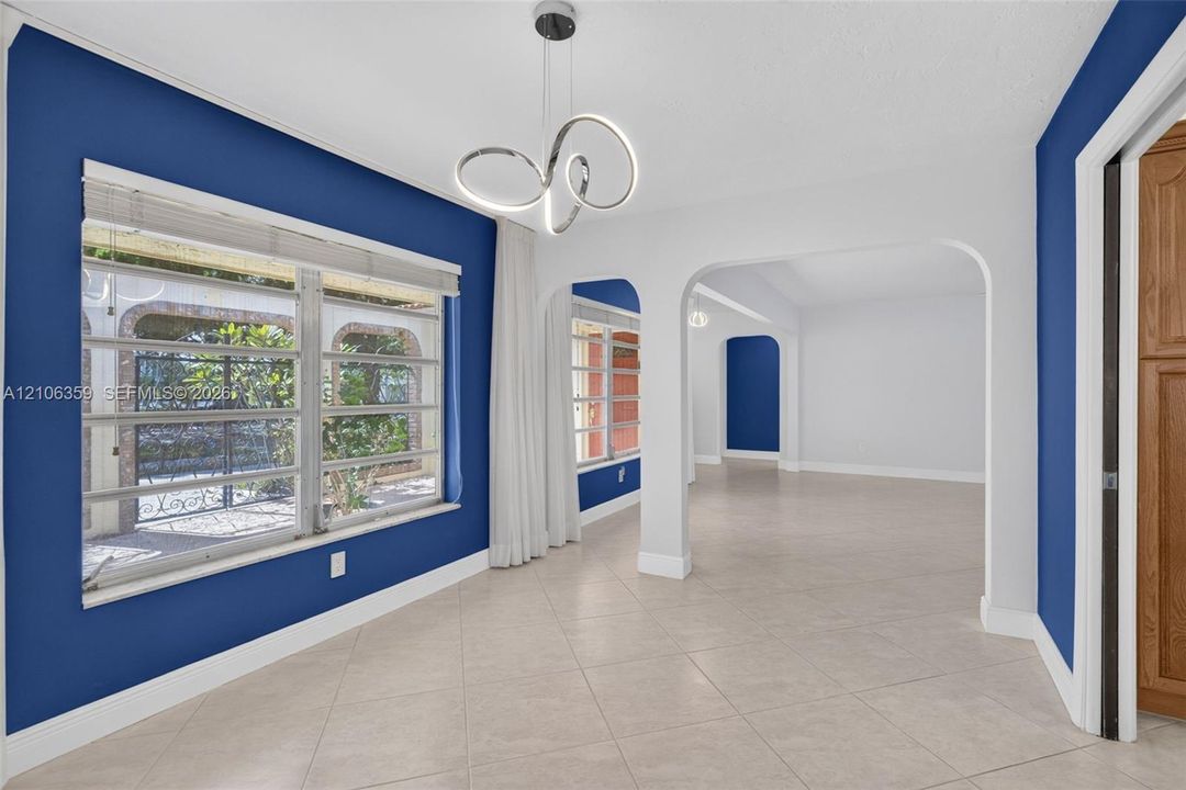 Open interior featuring large format tile flooring, arched architectural doorways, and a modern circular LED pendant light fixture