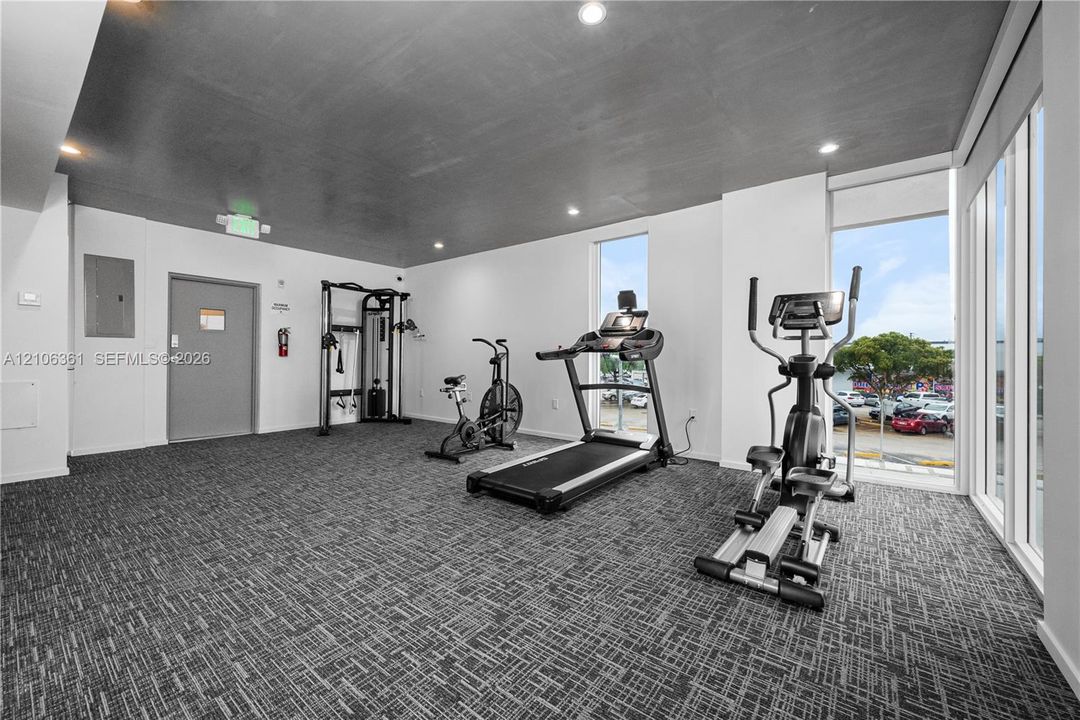 Fitness center featuring high ceilings, recessed lighting, patterned carpeting, and floor-to-ceiling windows