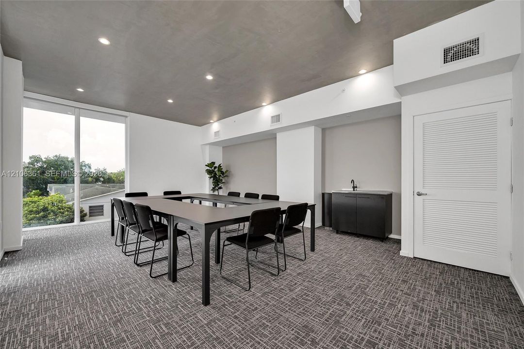 Floor-to-ceiling windows, recessed lighting, patterned carpeting, and a wet bar featuring dark cabinetry with a matte black faucet