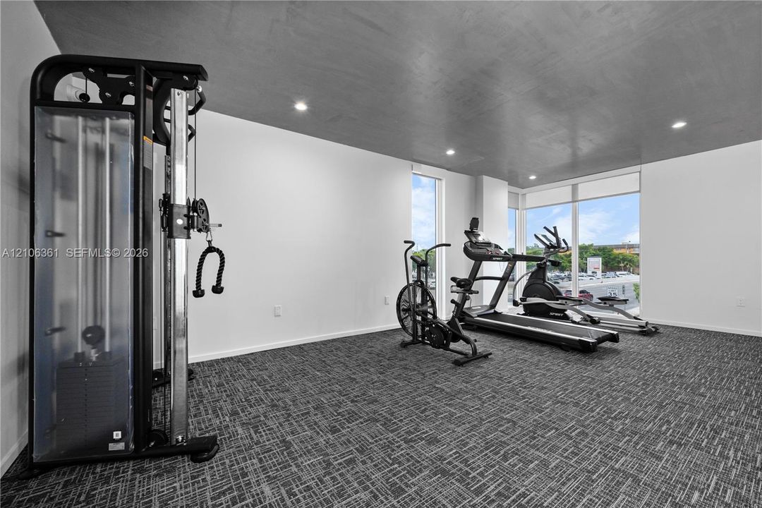 Fitness area featuring floor-to-ceiling windows, recessed lighting, a smooth dark ceiling, and patterned commercial-grade carpeting