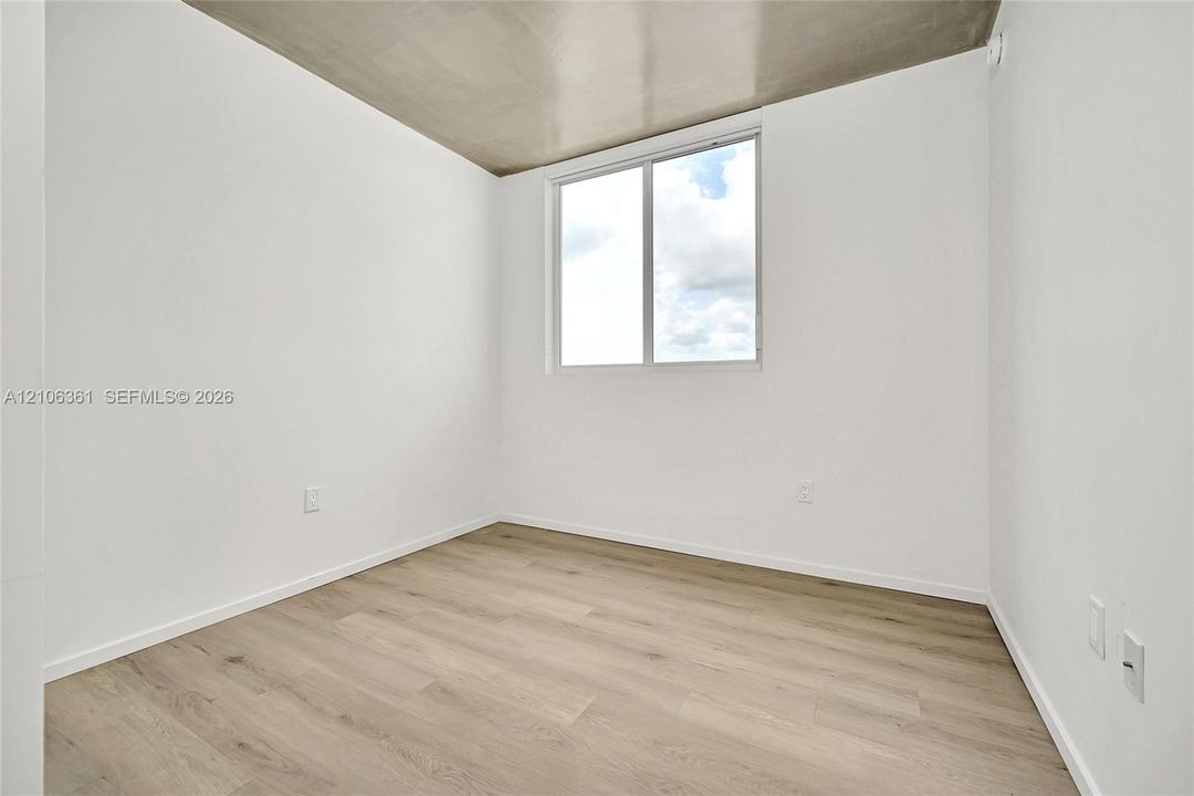 Room featuring high-gloss concrete ceiling, wood-finish flooring, and a single-pane window