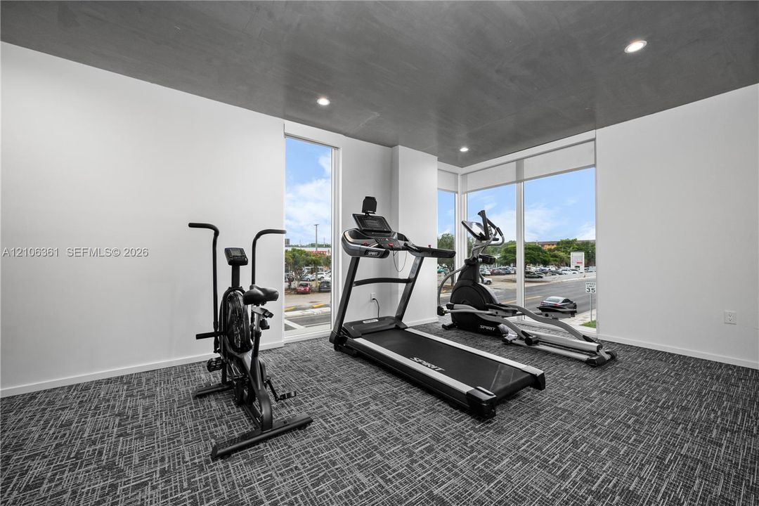 Floor-to-ceiling windows, high-contrast grey ceiling, recessed lighting, and patterned commercial-grade carpeting