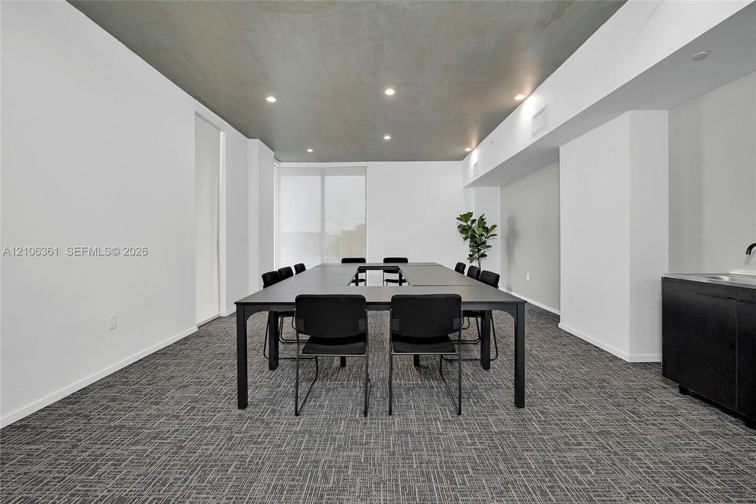 Neutral-toned room featuring a smooth grey ceiling, recessed lighting, textured carpet flooring, and a built-in black wet bar cabinet