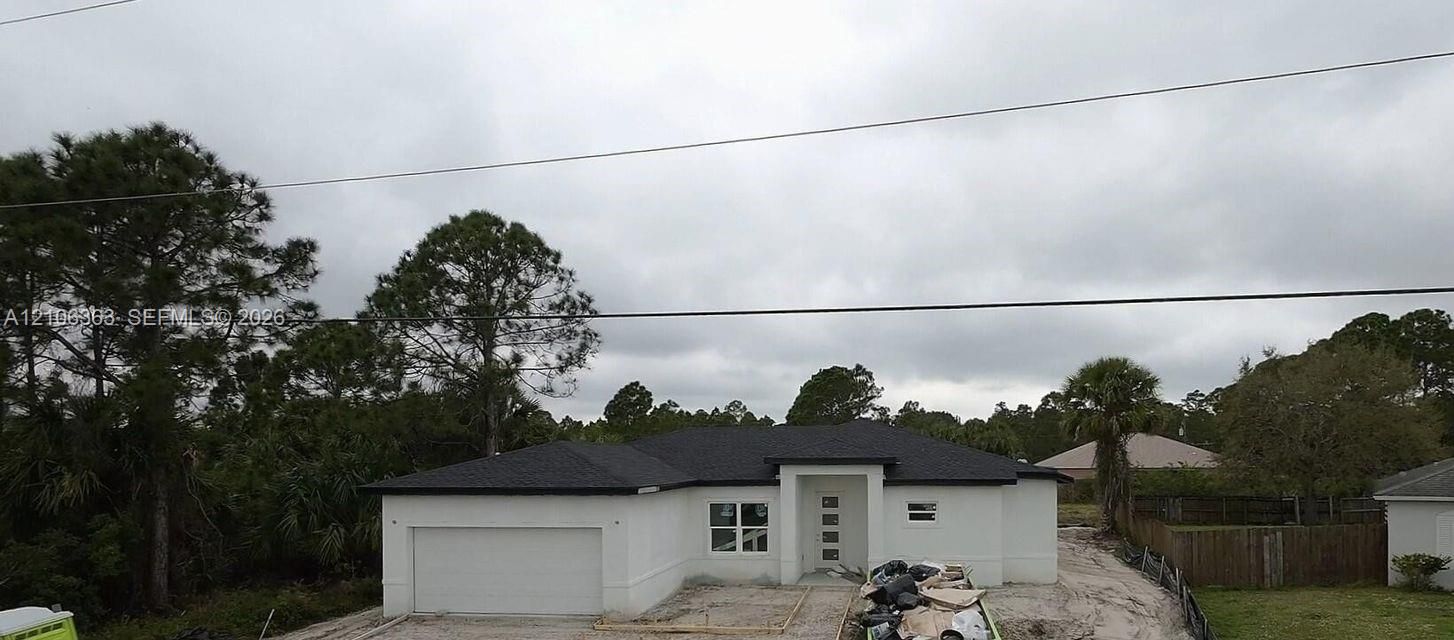 Single-story residence featuring a smooth stucco exterior, a multi-pane glass entry door, a multi-faceted roofline, and an attached two-car garage