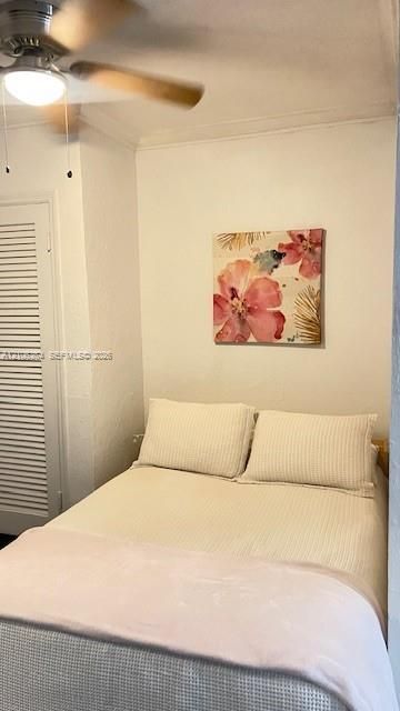 Interior space featuring a ceiling-mounted light fixture with fan blades and a closet with louvered doors