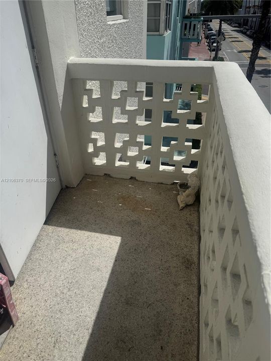 Private balcony featuring decorative geometric concrete screening and textured mineral-composite flooring