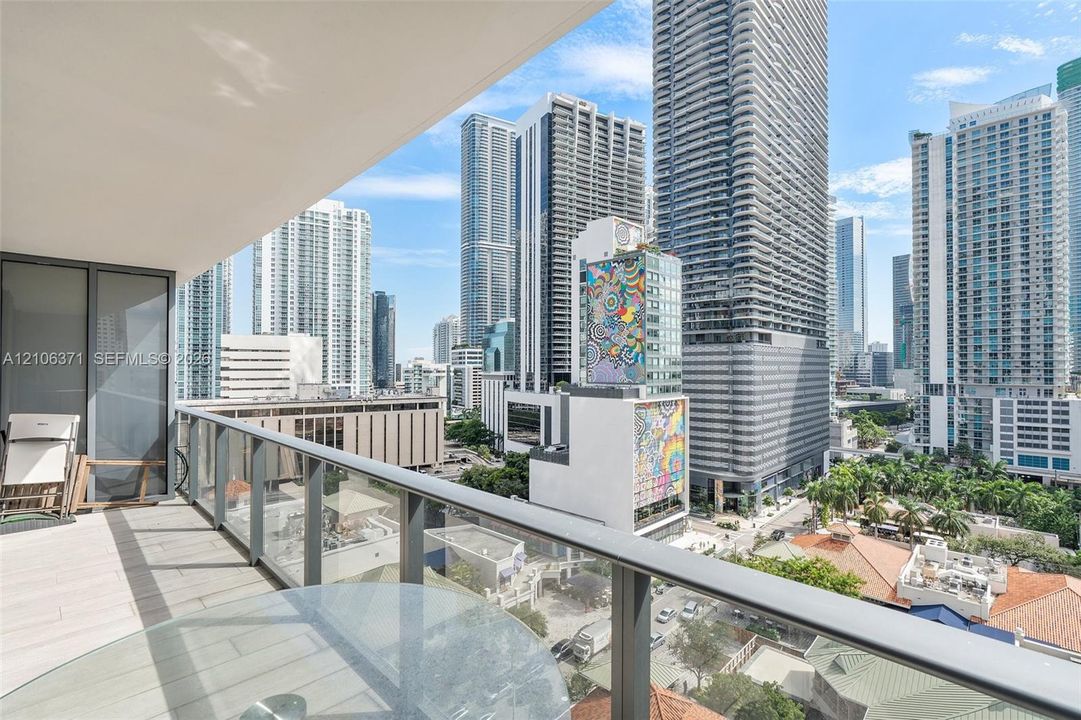 Covered balcony featuring large-format tile flooring and a glass-paneled metal railing