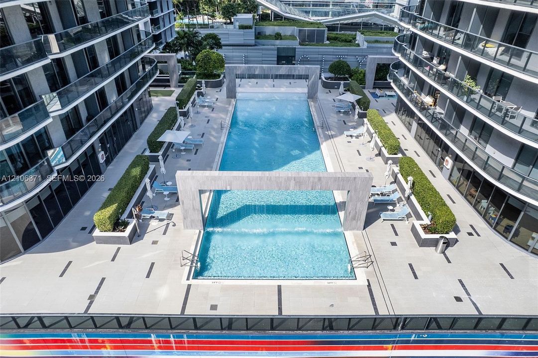 Rectangular swimming pool featuring a stone-clad water feature, paved terrace, and manicured landscaping
