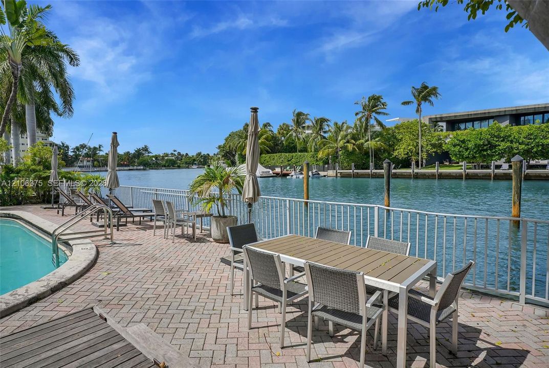 Waterfront patio featuring brick pavers, a built-in swimming pool, and private boat dockage