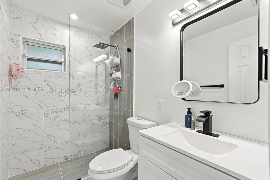 Bathroom featuring a vanity with a white composite countertop, integrated rectangular sink, and matte black faucet
