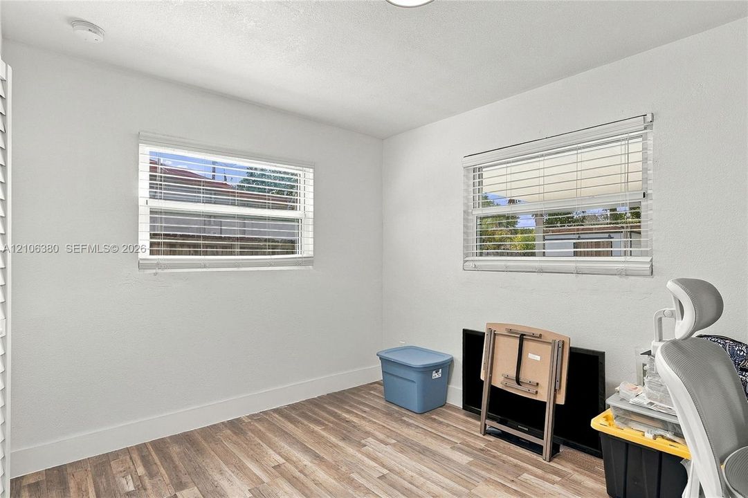 Room featuring wood-finish flooring, neutral walls, and dual windows with horizontal blinds