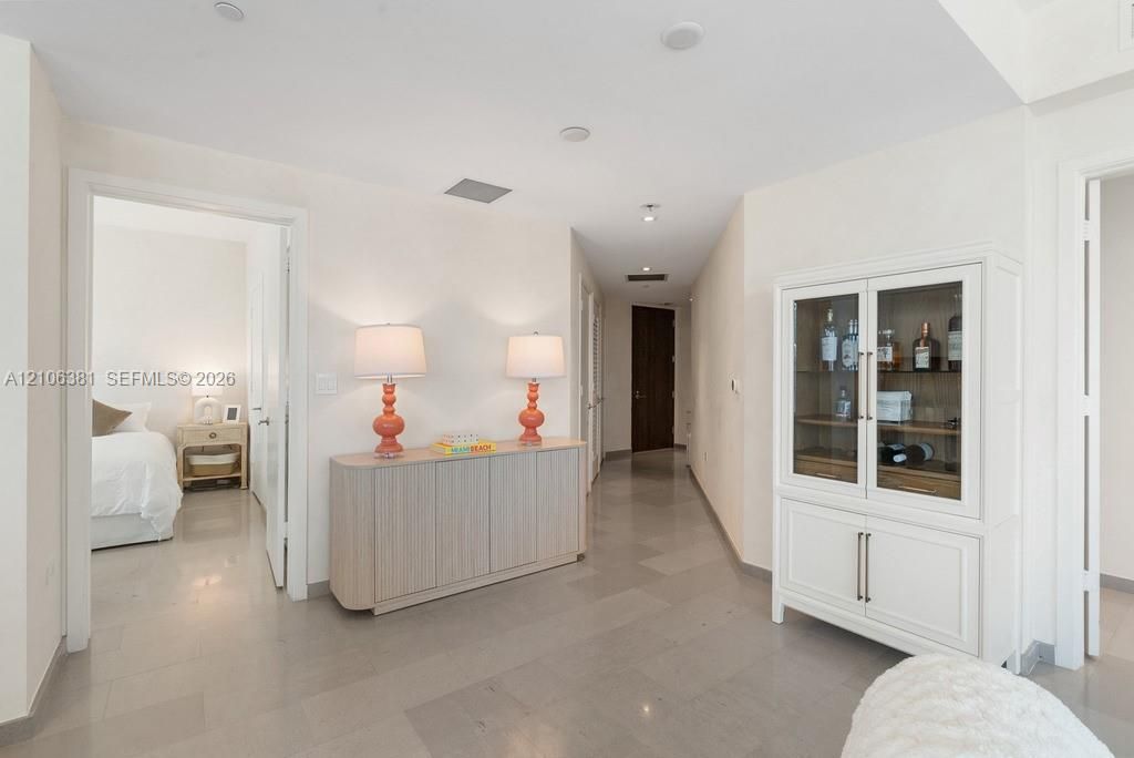 Hallway featuring neutral tile flooring, recessed ceiling lighting, and crisp white wall finishes